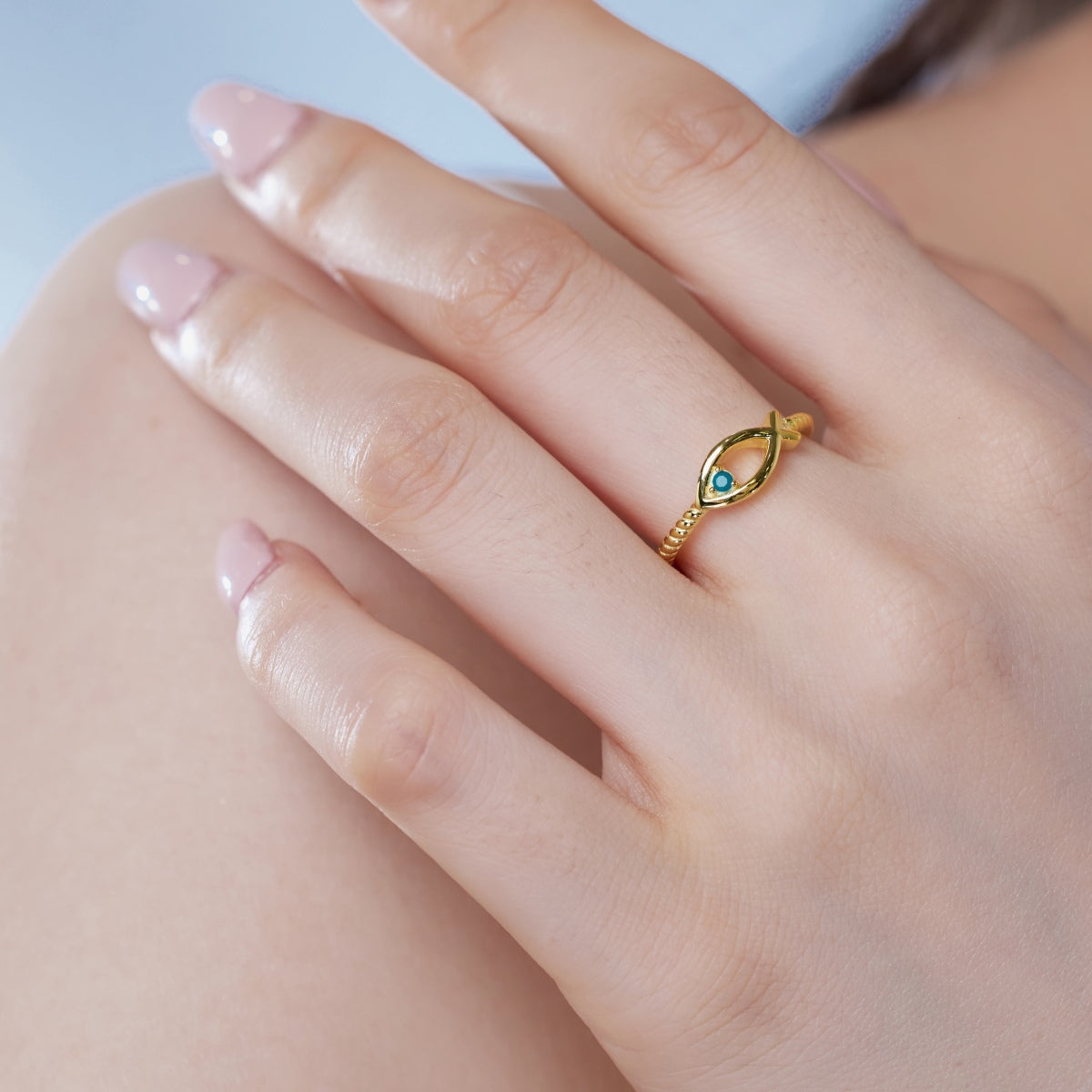 vista cercana del mano de una mujer lleva el Anillo Diseño Pez con Piedra Azul Turquesa de color dorado